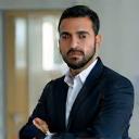 Photo of Omar Butti, a man in business casual clothing, looking thoughtful.
